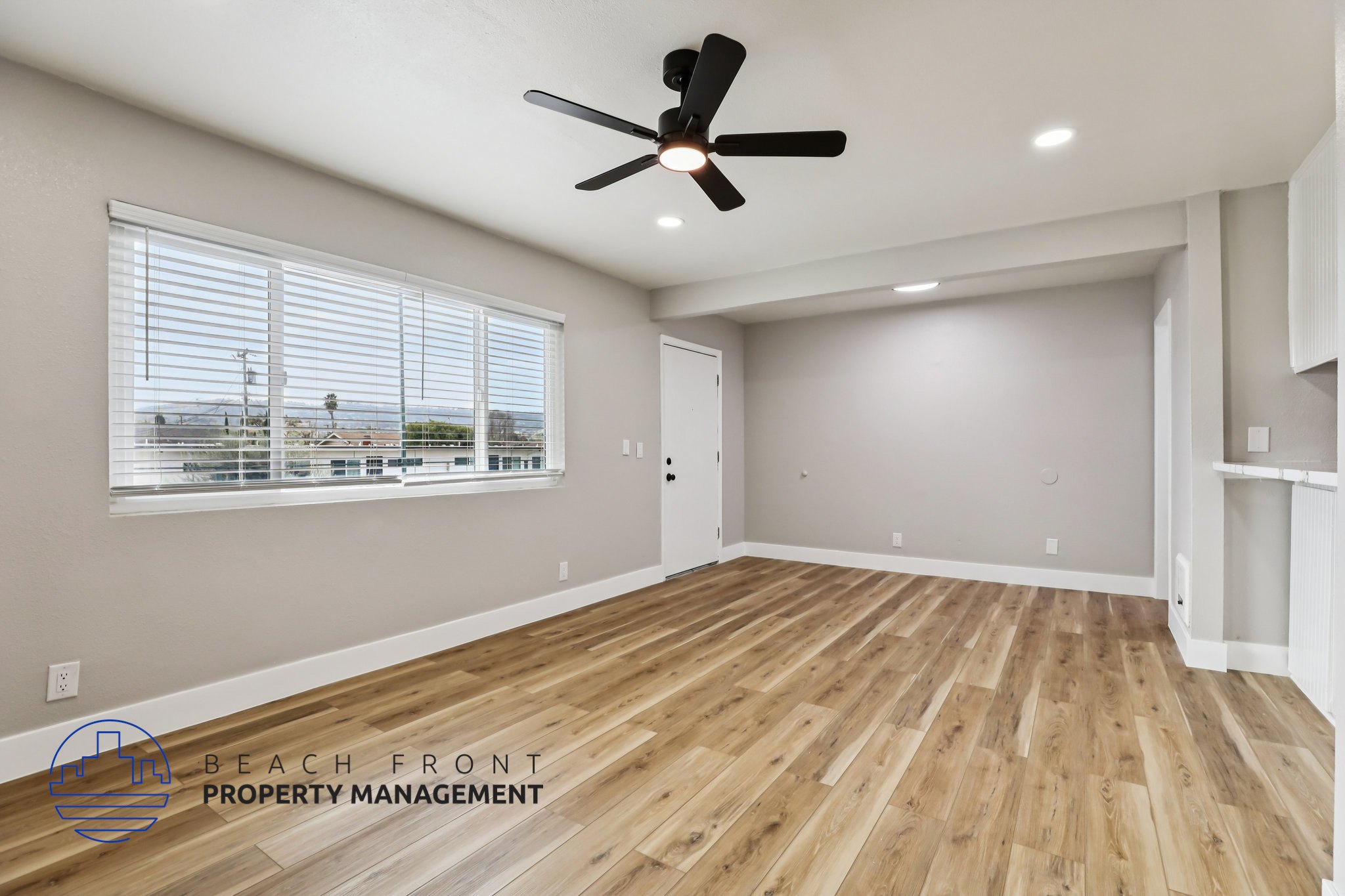 A spacious room with wooden flooring and a ceiling fan.